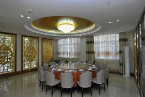 A round dining table with chairs, a chandelier, and decorative screens.