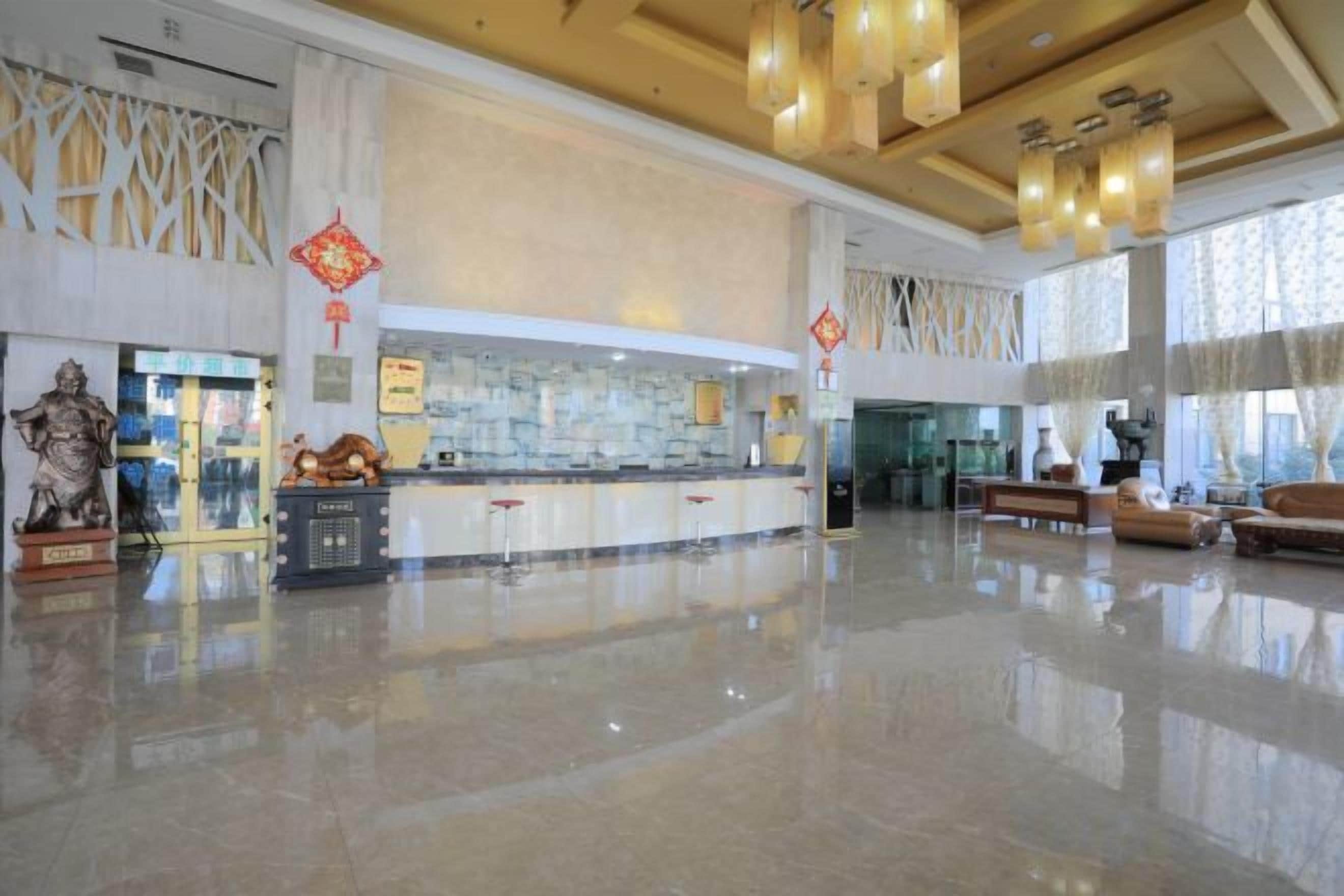 A spacious lobby with a reception desk, a statue, and a large window.