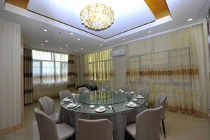 A conference room with a round glass table, beige chairs, and a chandelier. - You Yi Feng Hotel (Habahe)