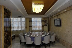A dining area with a round table, chairs, a chandelier, and a television on the wall. - You Yi Feng Hotel (Habahe)