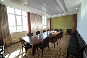 A conference room with a large table, chairs, a sofa, and a patterned carpet.
