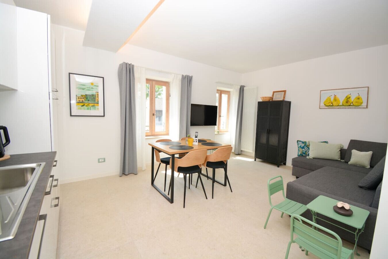 A compact living space with a kitchenette, a dining area, a sofa, and a TV.