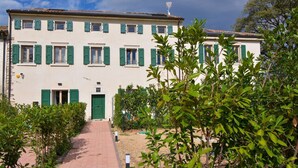 Un bâtiment à deux étages doté d’une entrée centrale, entouré de verdure et bordé d’un chemin pavé.