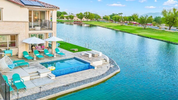 A two-story house with a swimming pool, outdoor furniture, and a view of a river. - Specials Barbie themed, Lakefront, games+pool (Indio)