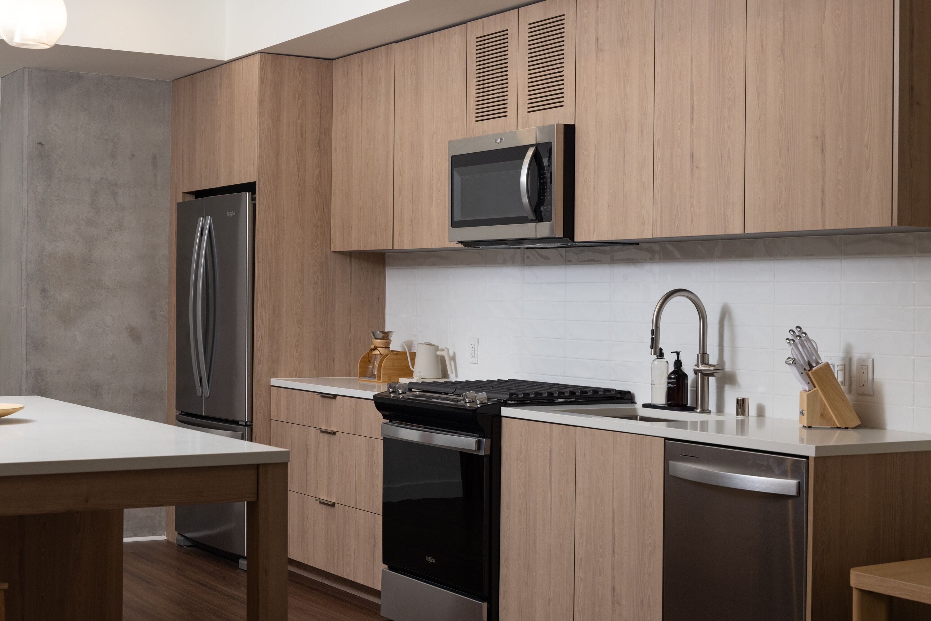 A modern kitchen with wooden cabinets, stainless steel appliances, a microwave, a sink, and a dishwasher.