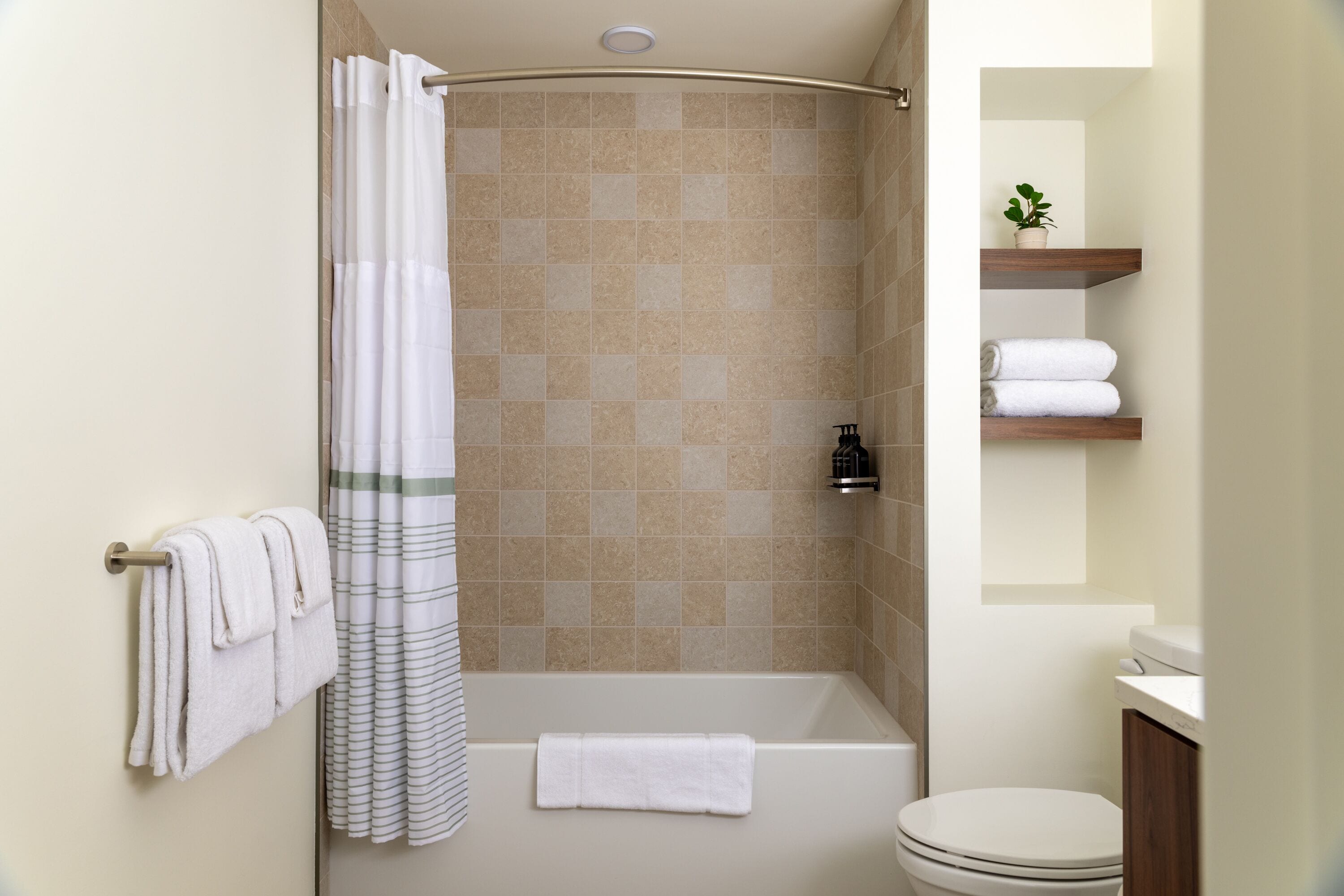 Une salle de bain avec une douche, des toilettes et une étagère avec des serviettes.