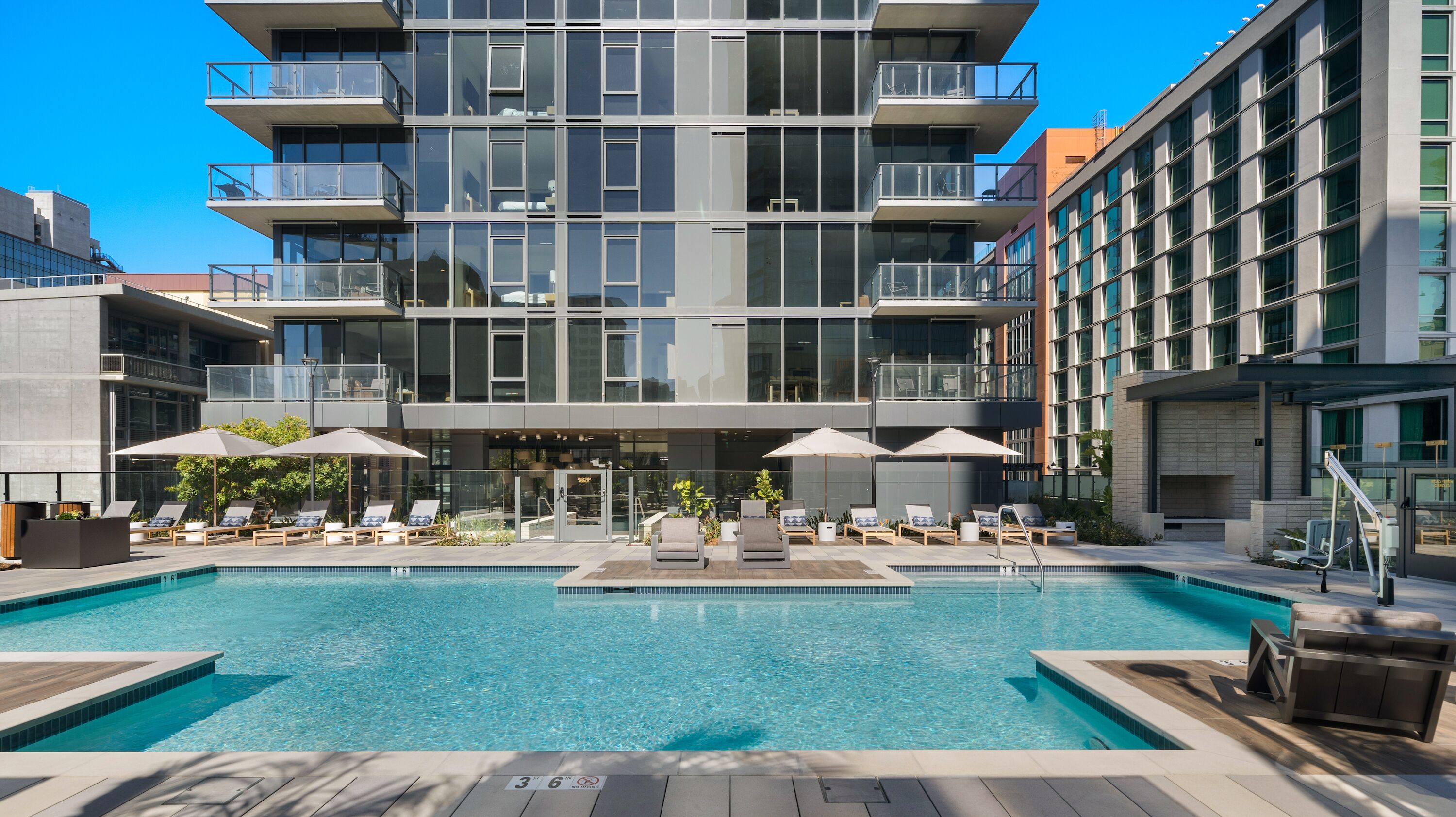 Um hotel moderno com piscina no terraço, área de estar externa e um edifício de vários andares.
