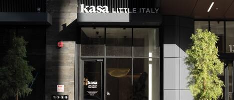 Un bâtiment moderne avec une enseigne indiquant « Kasa Little Italy » et une entrée en verre.