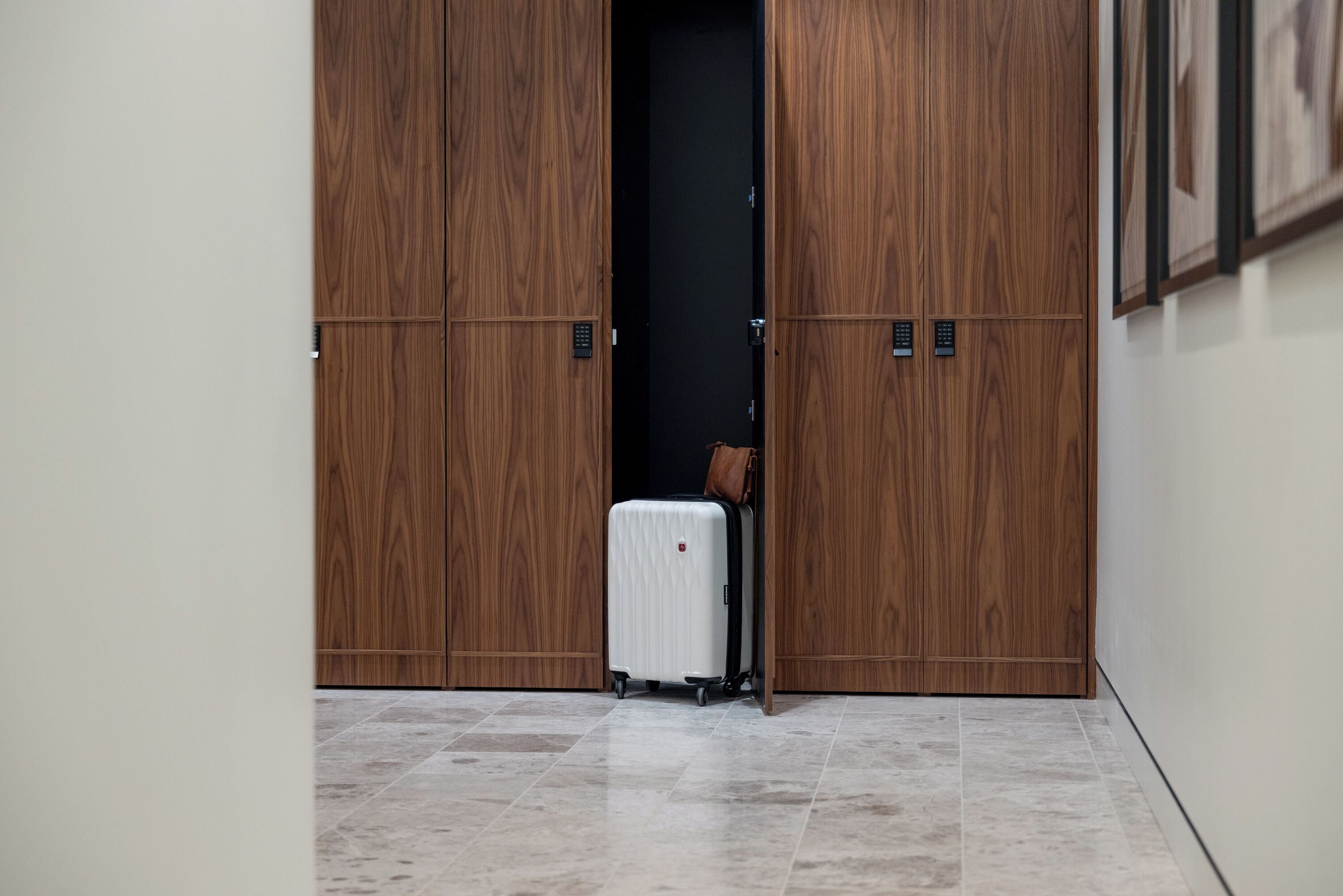 A hallway with a wooden wardrobe and a white suitcase on the floor.