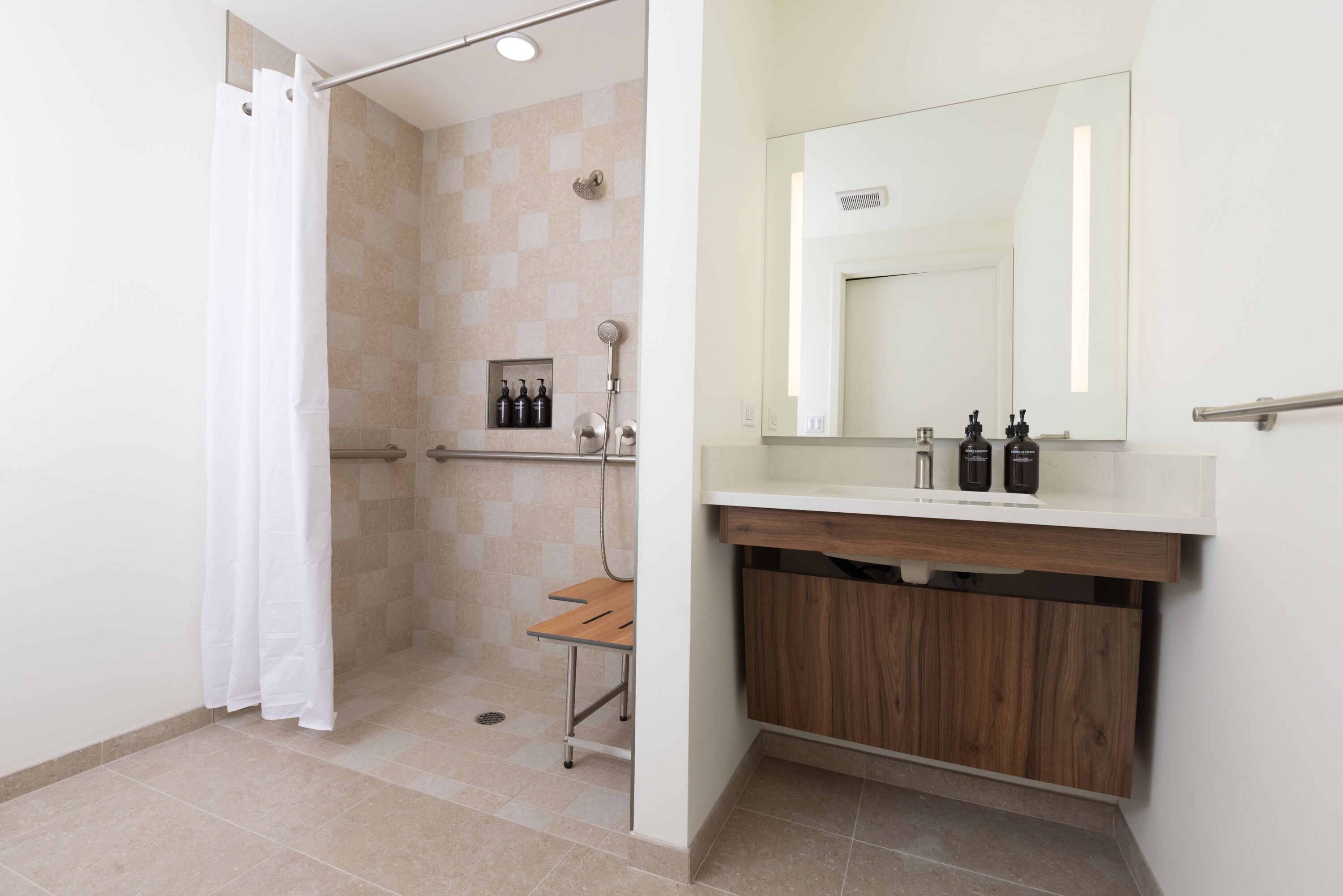 A bathroom with a shower, a vanity with a mirror, and a wooden cabinet.