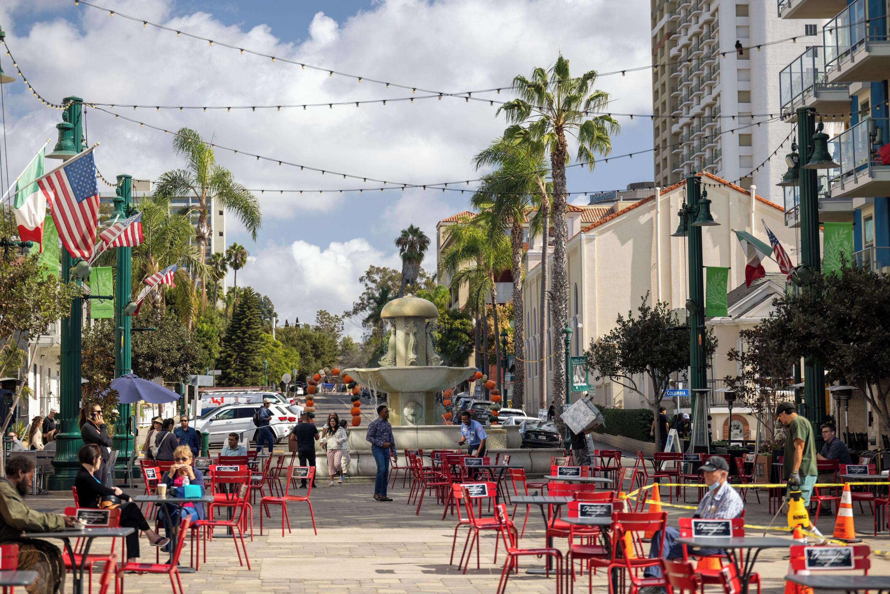 An outdoor seating area with red chairs and tables, a fountain, and flags.