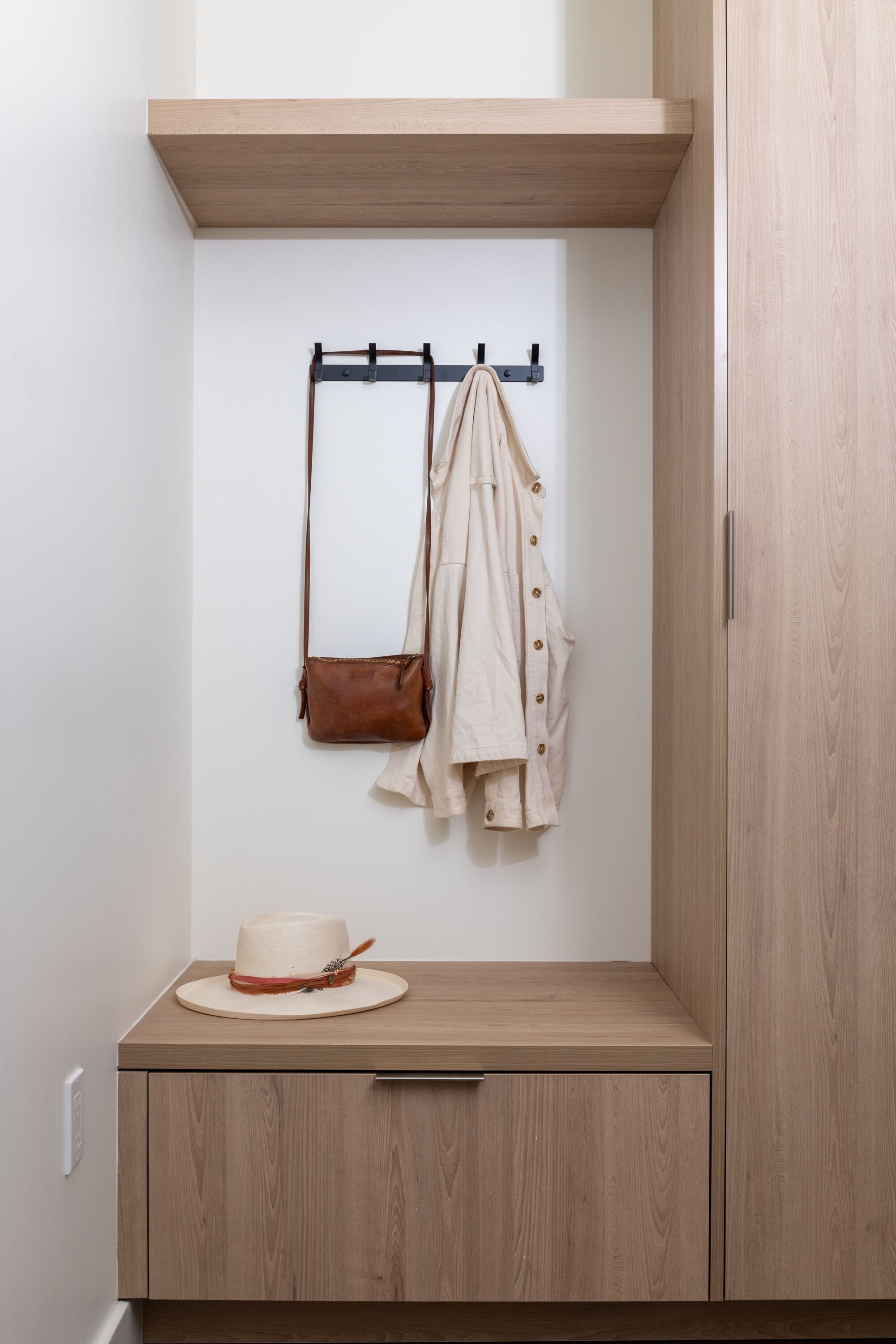Un mueble de madera con un sombrero color crema y un bolso marrón encima.