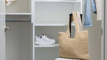 A white wardrobe with shelves, a hanging bag, and a suitcase.