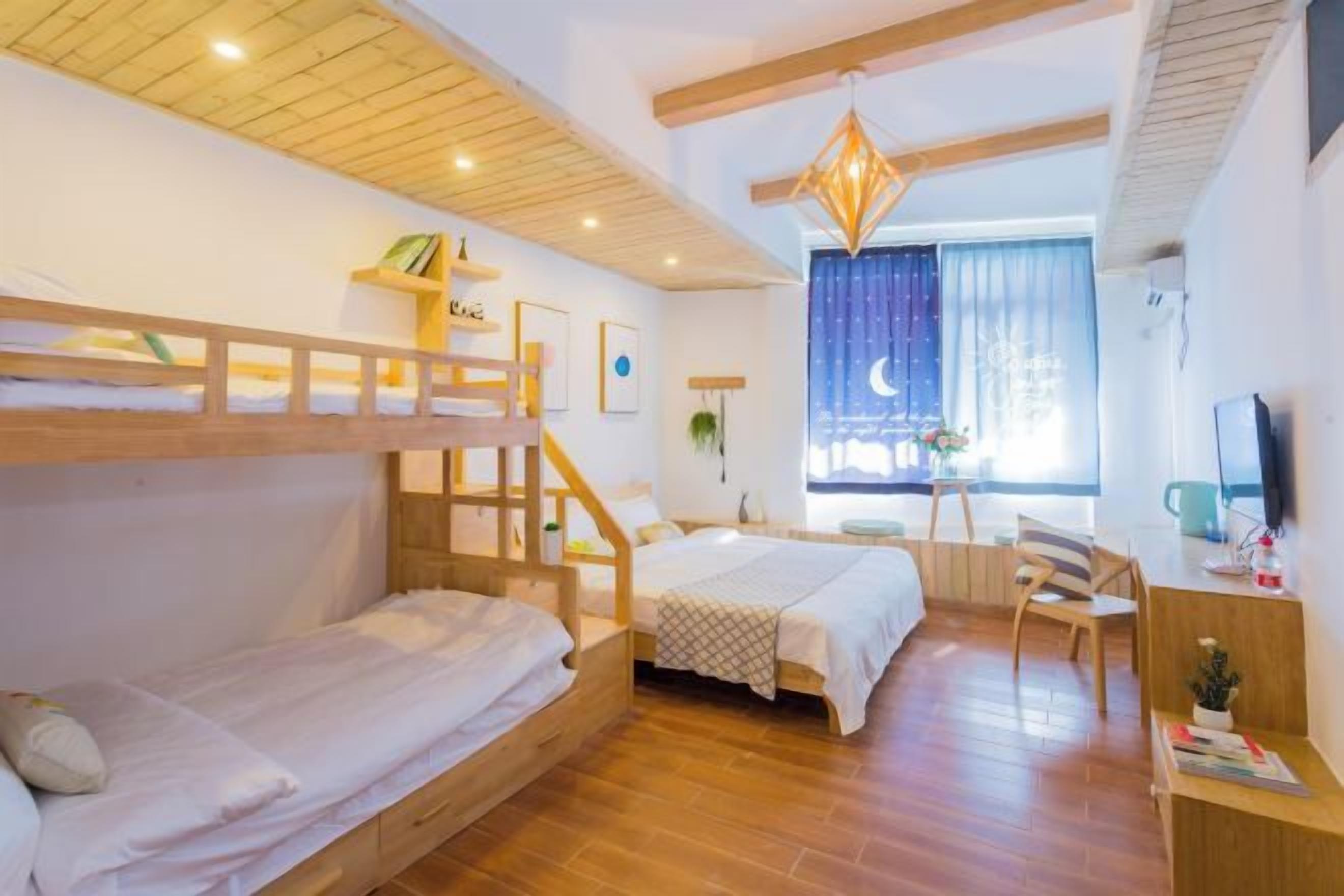 A cozy room with two bunk beds, a desk, and a chair. There is a window with curtains and a plant on the desk.