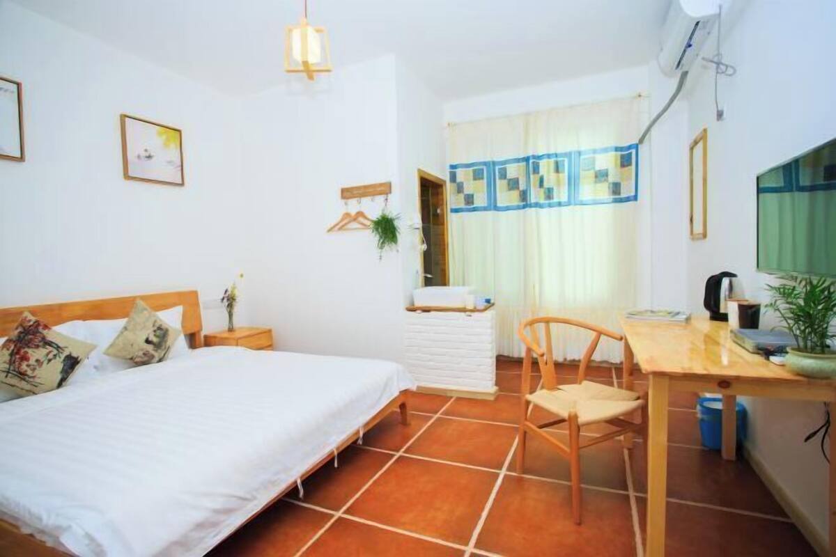 Ein Schlafzimmer mit Bett, Nachttisch, Stuhl und Schreibtisch mit Sitzgelegenheit.