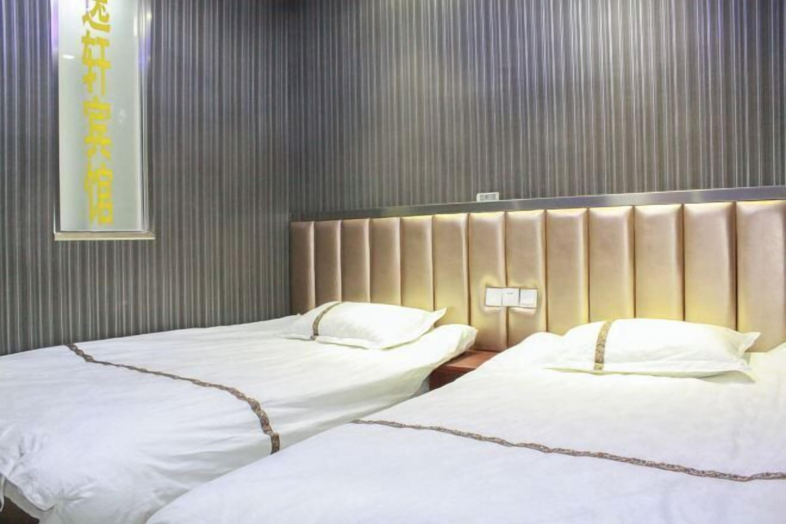A hotel room with two beds, a striped wall, and a sign with Chinese characters.