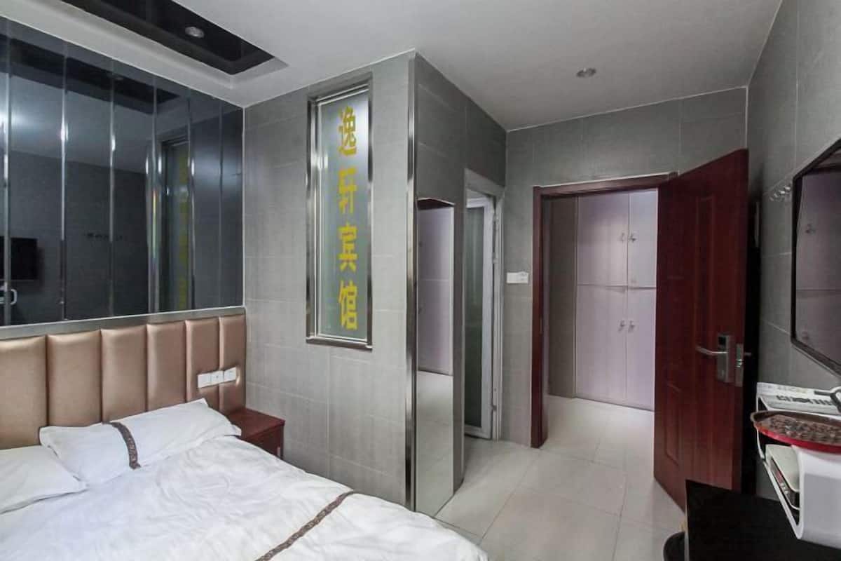 A hotel room with a bed, a wardrobe, a mirror, and a wall-mounted sign.
