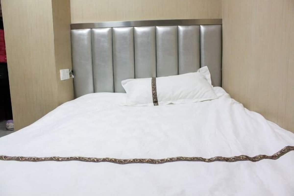 A neatly made bed with a padded headboard and a decorative border.