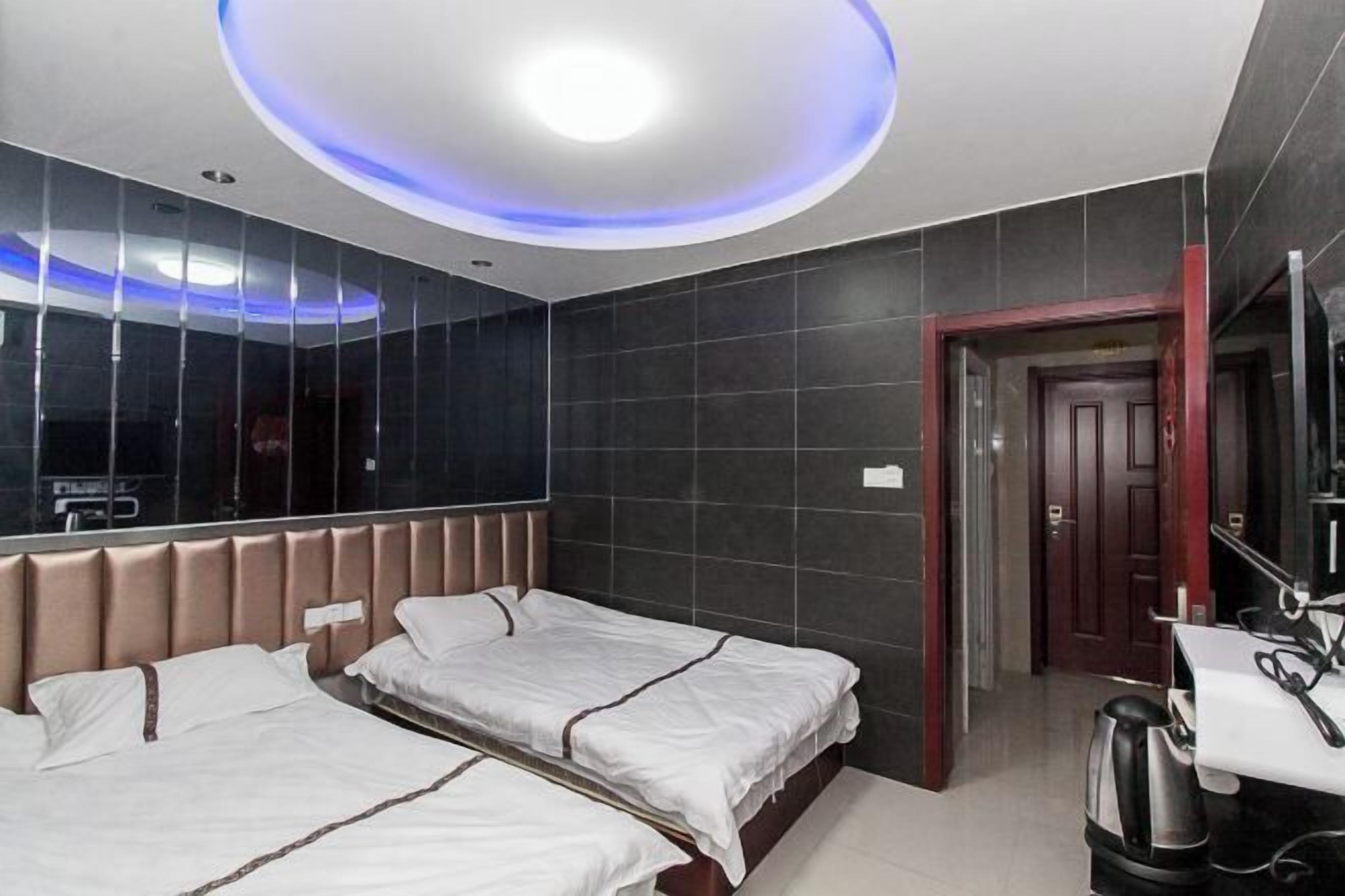 Une chambre d’hôtel avec deux lits, un design moderne au niveau du plafond, un grand miroir et une machine à café.