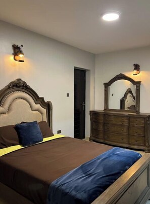 Restful retreat with a large bed, dresser, and mirror.