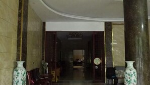 A lobby with marble columns, a reception desk, and a sign indicating a smoking area. - Changning Yanyi Hotel (Changning)