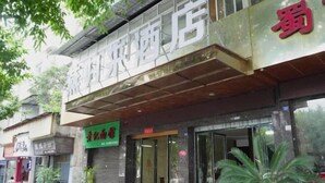 A hotel facade with a large sign, potted plants, and a visible entrance. - Changning Yanyi Hotel (Changning)