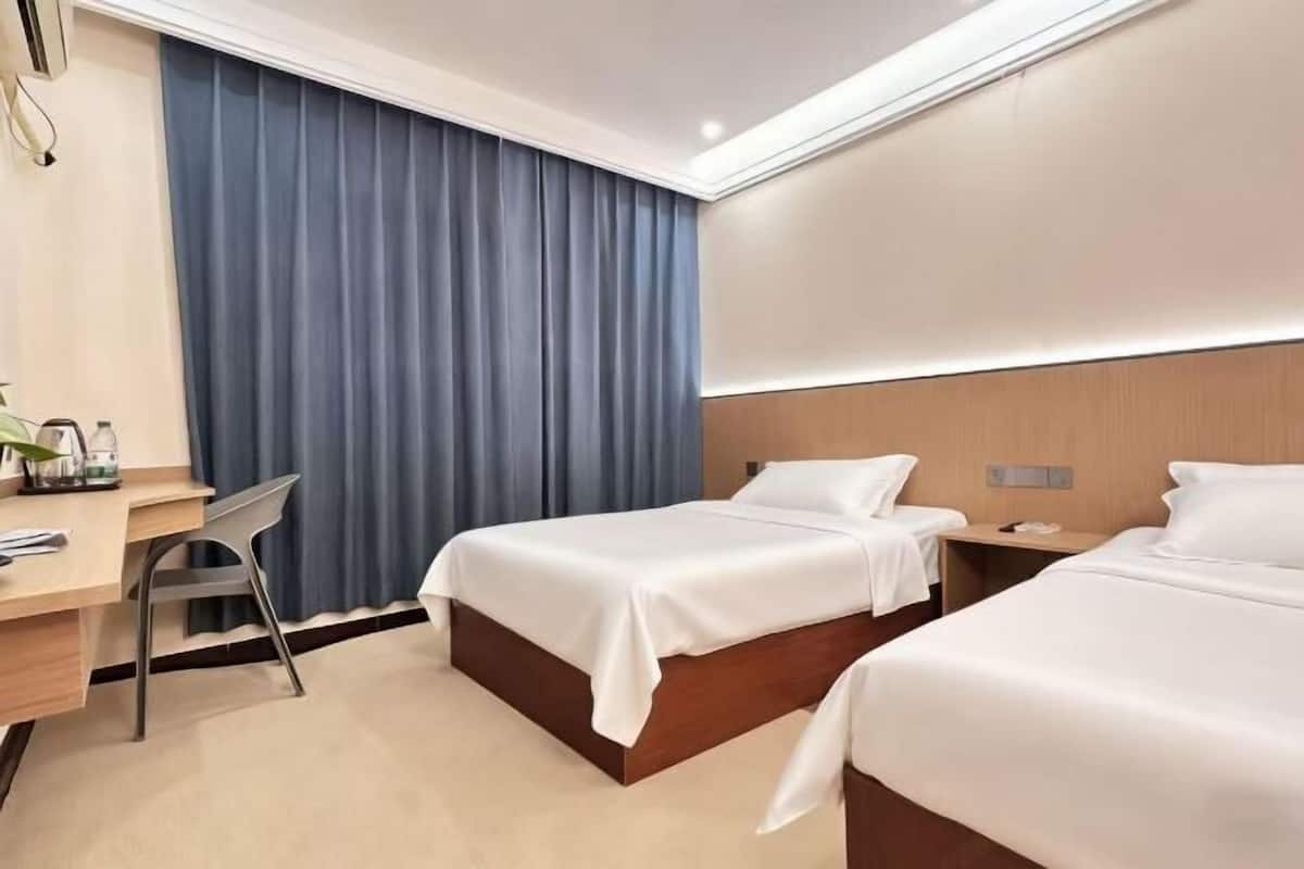 Hotellihuone, jossa on kaksi sänkyä, työpöytä ja tuoli.