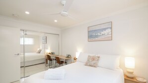 Ein Schlafzimmer mit Bett, Nachttisch, Lampe und Schreibtisch mit Stuhl.