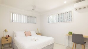 Une chambre à coucher comprenant un lit, des tables de chevet, un bureau et une chaise.