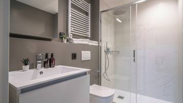 A modern bathroom with a white sink, a toilet, and a glass-enclosed shower.