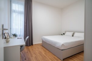 Quarto moderno com uma cama, uma escrivaninha e uma cadeira.