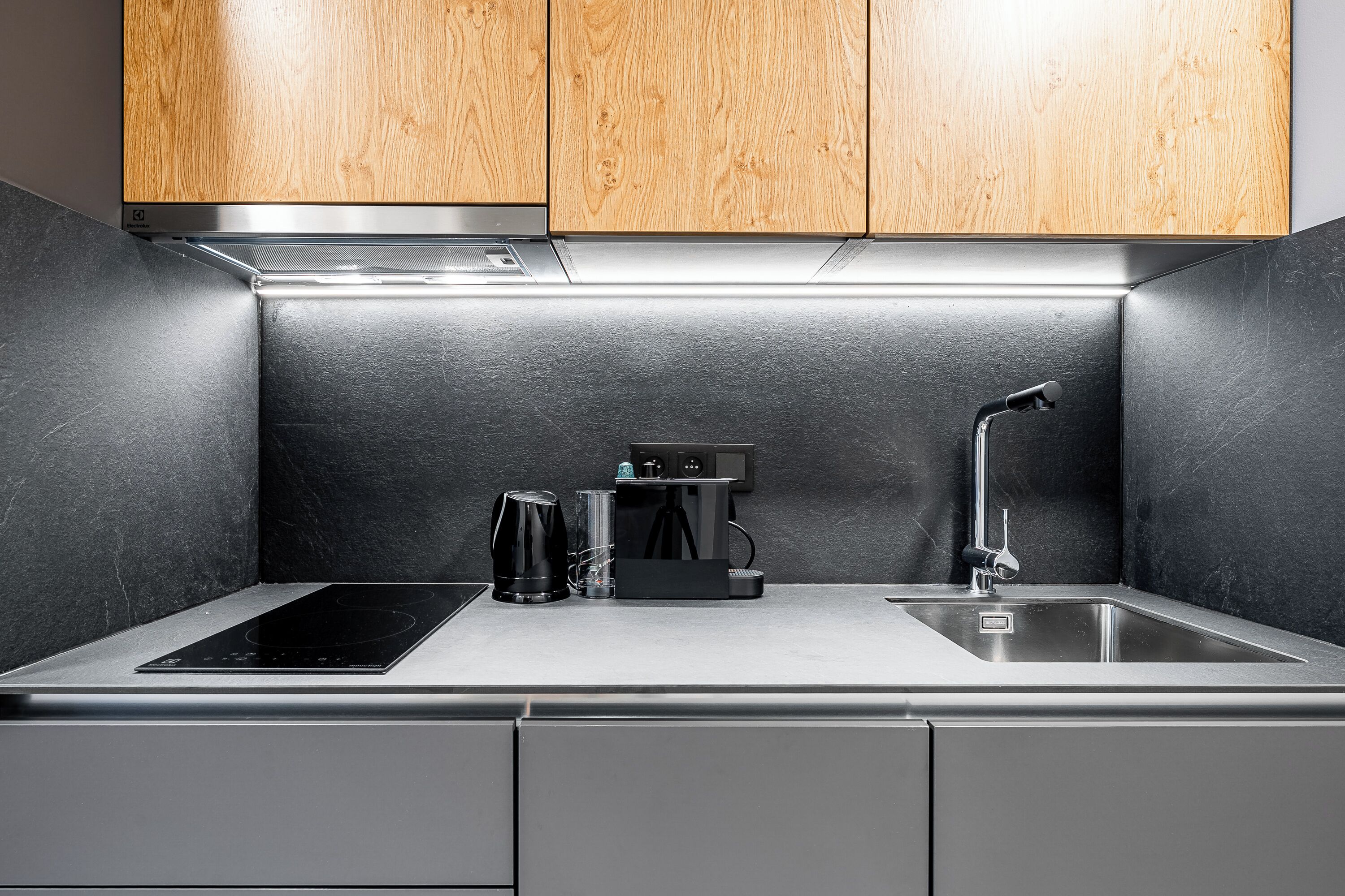 A modern kitchen with a built-in stove, a coffee maker, and a sink.