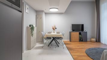 A modern living room with a dining area, a flat-screen TV, and a wooden cabinet.