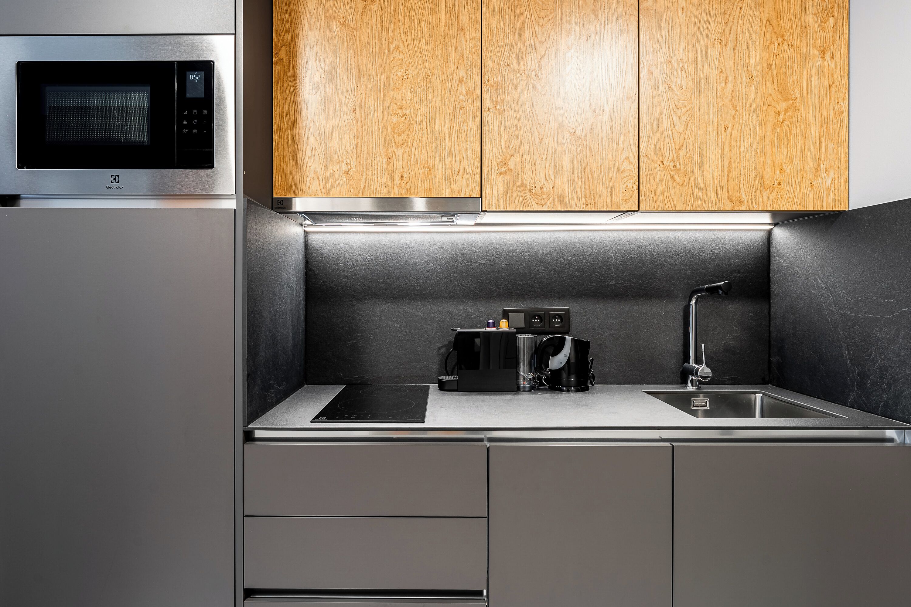 A modern kitchen with a built-in microwave, a coffee maker, and a sink.