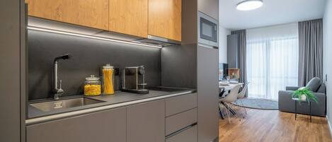A modern kitchen with grey cabinets, a stainless steel sink, and a built-in microwave.