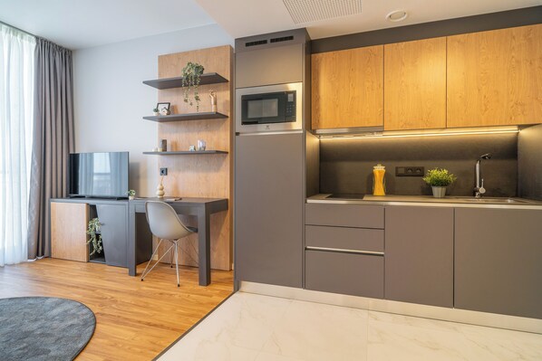 Una cocina moderna con microondas integrado, un lavamanos y armarios de madera.