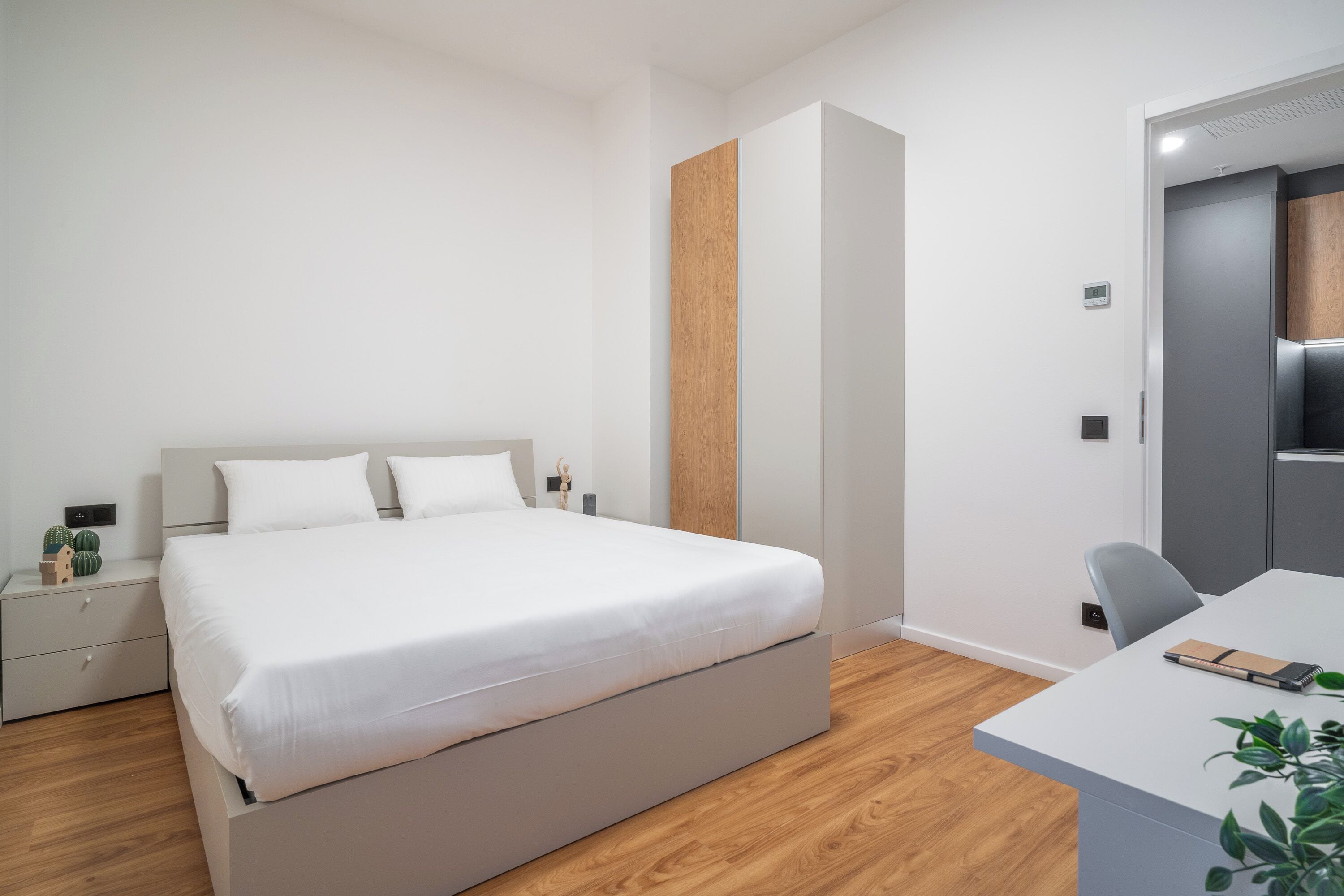 A modern bedroom with a large bed, bedside tables, a desk, and a chair.