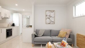 Eine moderne Küche mit weißen Schränken und ein graues Sofa im Wohnbereich.