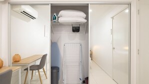 A compact room with a desk, chair, and a drying rack.