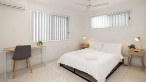 A bedroom with a bed, a desk, and two bedside tables.