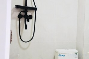 Un baño con ducha, inodoro y estante en la pared.