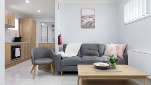 A modern living room with a grey sofa, a wooden coffee table, and a grey armchair.