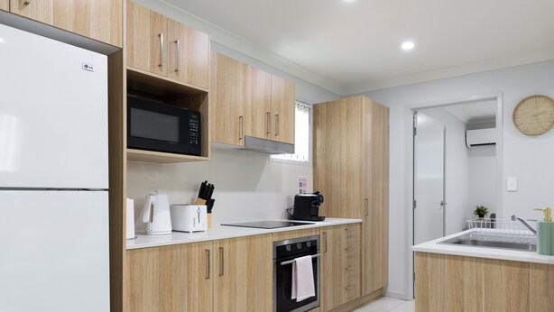 A modern kitchen with wooden cabinets, a built-in microwave, a coffee maker, and a dishwasher.
