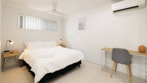 Una camera da letto con un letto, comodini, una scrivania e un condizionatore d'aria.