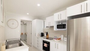 Una cucina moderna con mobili bianchi, elettrodomestici in acciaio inossidabile e forno integrato.