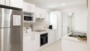 Een moderne keuken met witte kasten, roestvrijstalen apparatuur, een magnetron en een inbouwoven.