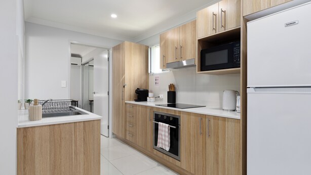 Une cuisine moderne avec des meubles en bois, un four encastré, un four à micro-ondes et un réfrigérateur.