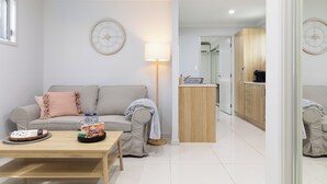 Un salon moderne avec un canapé, une table basse et un petit coin cuisine à l’arrière-plan.
