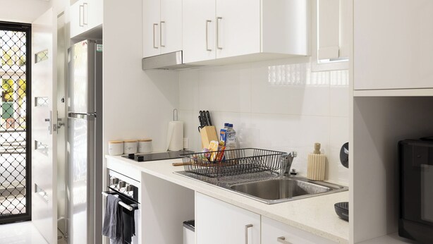 Une cuisine moderne avec des meubles blancs, des appareils électroménagers en acier inoxydable et un lave-vaisselle noir.