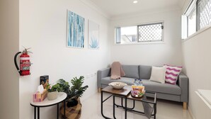 Un salon moderne avec un canapé gris, une petite table basse et un extincteur fixé au mur.